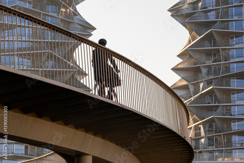 Bicycle commuter riding through curved urban bridge in Copenhagen, Denmark, reflecting future mobility, urban balance and sustainable architectural integration.