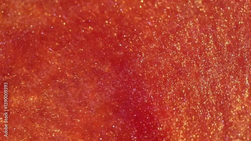 liquid with dissolved particles of red orange candurin and bubbles slowly moves and shines. abstract bright background