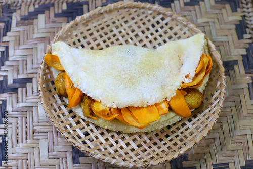 Tapioca, a popular dish in Brazil, especially common in the Manaus region of Amazonas. The tapioca is presented in a small, shallow, round basket made of woven straw. The basket has an open grid patte