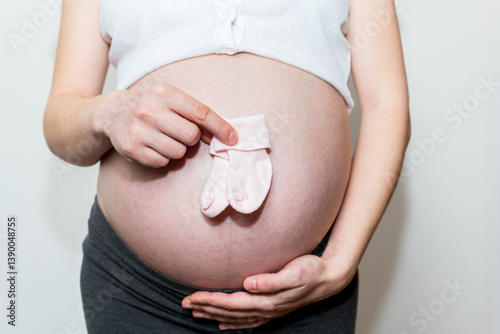 tiny baby socks against the background of a pregnant belly, pink socks