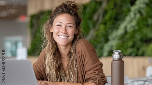 A happy young woman works on her laptop in a bright, modern café, embodying the joy of remote work while enjoying her surroundings and social atmosphere. photo