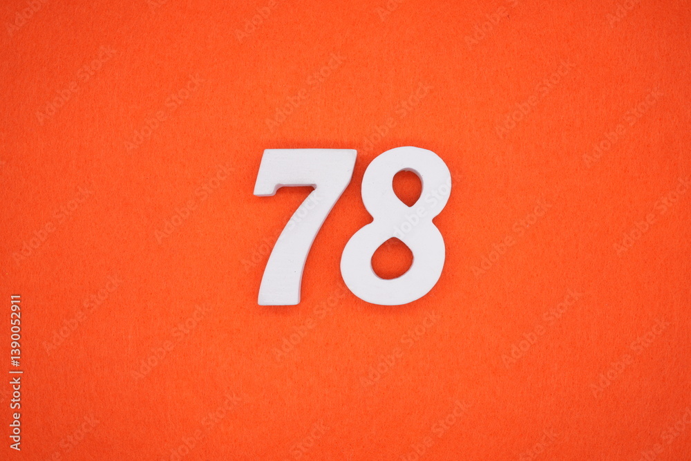 The numbers are made of white painted wood placed on an orange paper background.