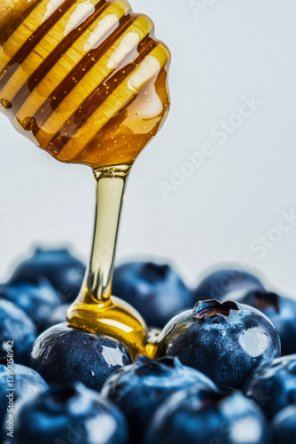 Obraz na płótnie Honey dripping from a wooden dipper onto a pile of fresh, dark blue blueberries. w salonie