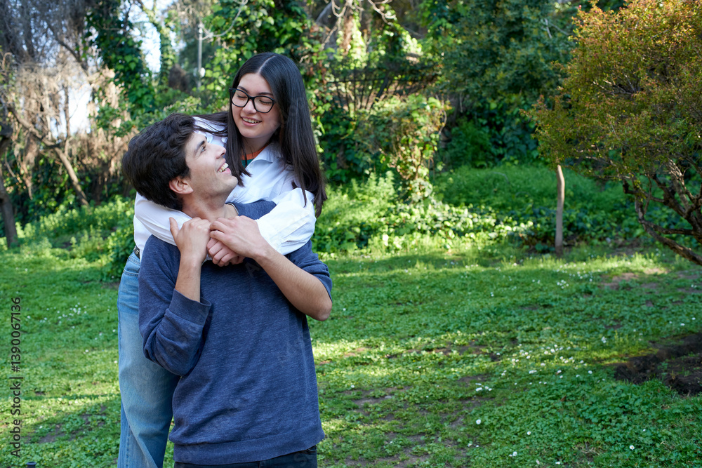 Young couple enjoying a playful moment in a green park, sharing smiles and affection