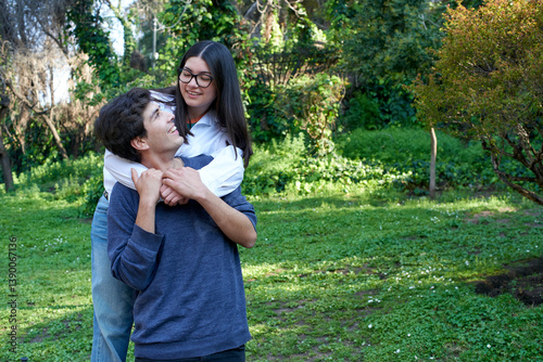 Young couple enjoying a playful moment in a green park, sharing smiles and affection