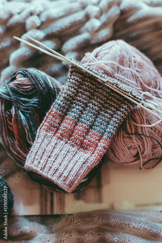 Hand knitted sock with needles and yarn ball. Close up.