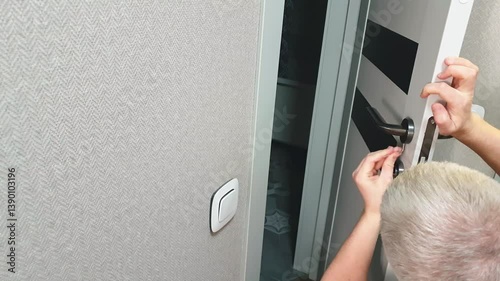 Man tightens up door handle with angle key. indoor