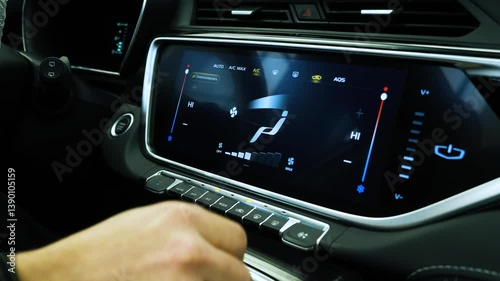 A close-up view of a hand interacting with a touchscreen climate control panel inside a premium SUV