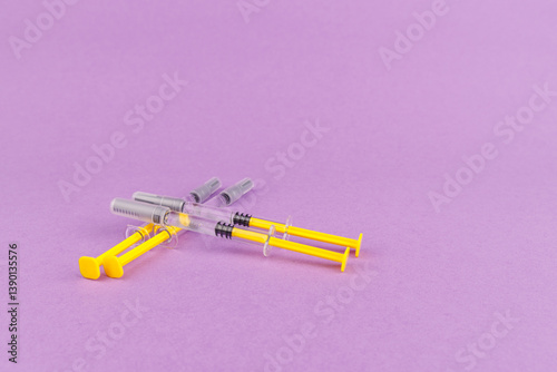 Glass syringes filled with heparin on violet background, medical instruments for anticoagulant use in sterile health settings