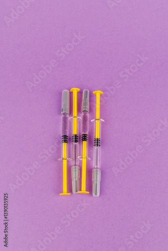 Glass syringes filled with anticoagulant heparin on violet table, laboratory health tools in sterile arrangement