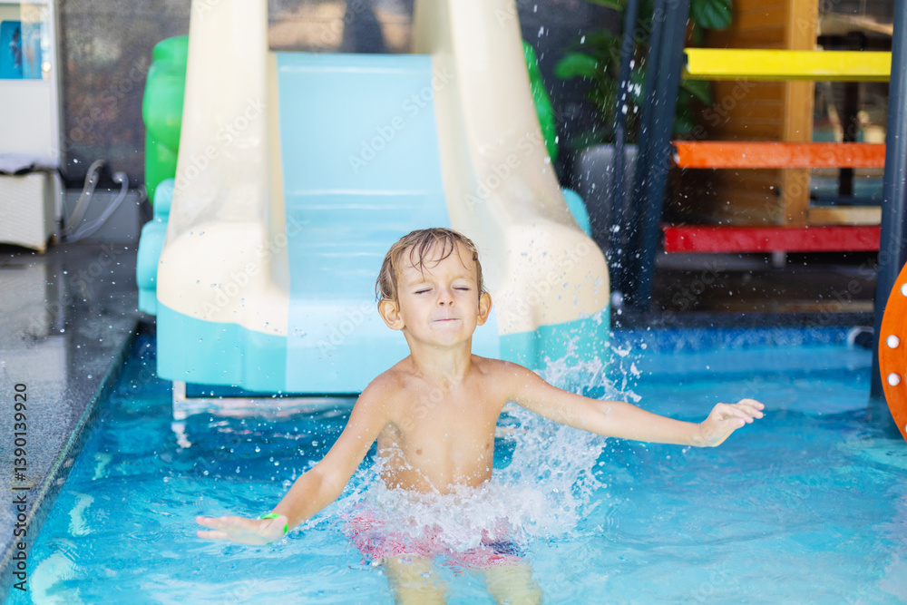 Boy splashing in pool from water slide
