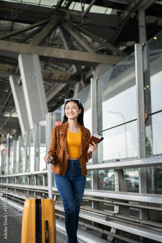 Fényképezés Happy young asian woman traveler using smartphone and holding boarding pass whil