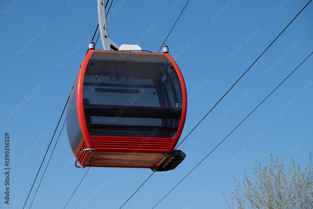 Close up of empty red gondola cabin suspended in blue sky Close up of empty red gondola cabin suspended in blue sky