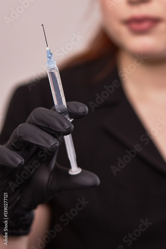 Obraz na płótnie Hand in black glove holding syringe with blue liquid, medical injection preparation, healthcare concept w salonie
