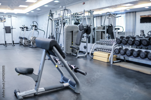 Empty gym with strength training machines, free weights, and cardio equipment in bright room. photo