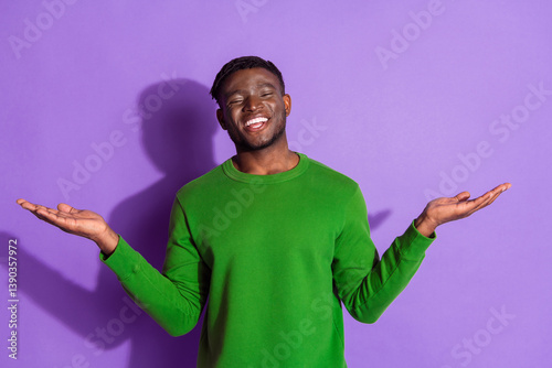 фотографія Young man with a happy expression in a green sweater against a vibrant purple background striking an expressive gesture