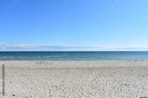 Fototapeta Naklejka Na Ścianę i Meble -  Sandy beach and blue sky. Sea in spring morning. Sunny day on the Baltic Sea. Horizon. Sea water. Waves. Travel and recreation.
