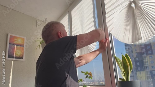 Man closes the window on the balcony. Indoors
