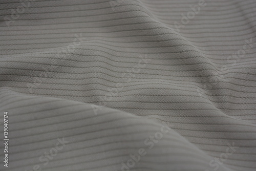 Materials, light green, brown thin fabric with texture and structure, small lines. Unusual fabric stele made of synthetic fibers and located on a white plastic background.
