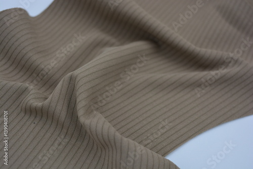 Materials, light green, brown thin fabric with texture and structure, small lines. Unusual fabric stele made of synthetic fibers and located on a white plastic background.