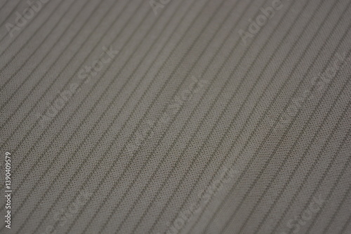 Materials, light green, brown thin fabric with texture and structure, small lines. Unusual fabric stele made of synthetic fibers and located on a white plastic background.