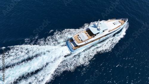 Obraz na płótnie Aerial drone tracking photo of beautiful modern super yacht with wooden deck cruising in low speed deep blue Mediterranean sea w salonie