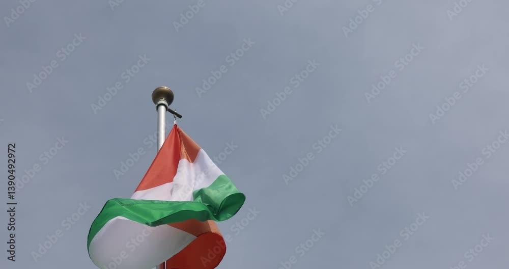 The national flag of Ivory Coast flutters in the wind. Great for news. Close-up. The flag of Ivory Coast against the blue sky. 4K video.