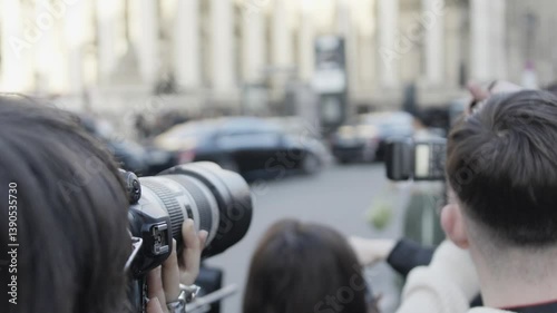 Paparazzi taking photos of a celebrity arriving in a black car