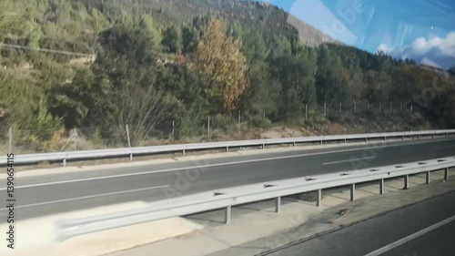 Bus ride video through Catalonia, Spain, showcases autumnal hills with yellow and brown trees along a scenic highway. Video 12 sec. Sunny skies and moving trucks blend nature with a calm road journey