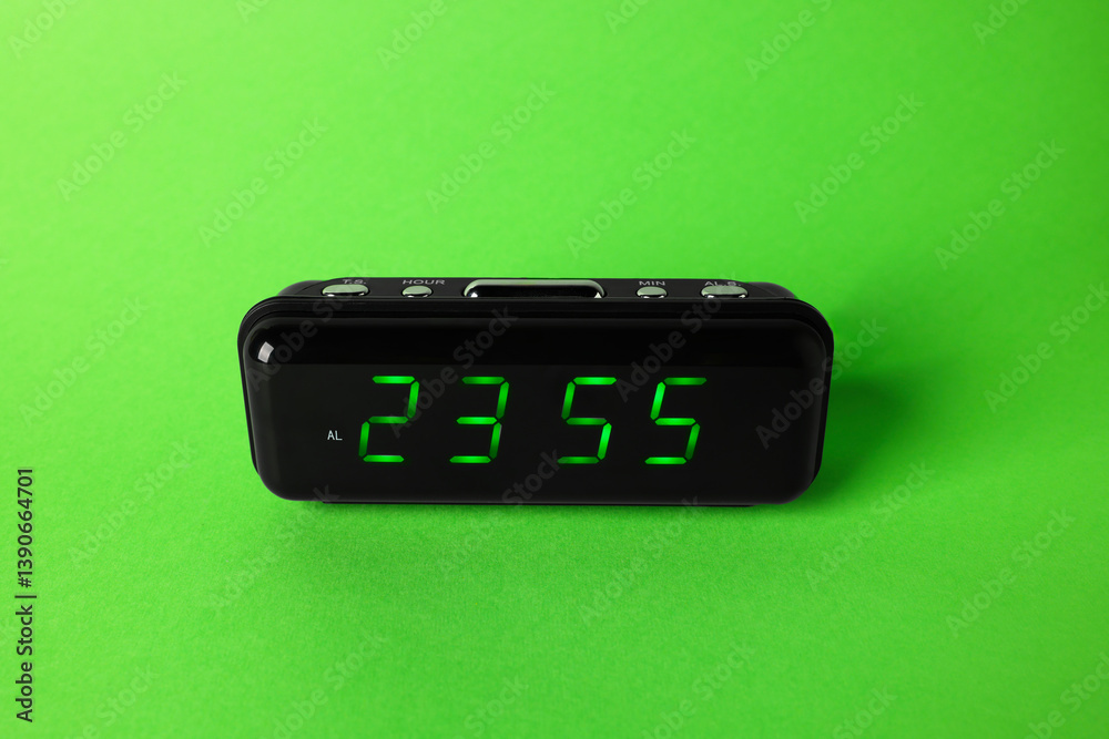 Digital alarm clock showing 23:55 o'clock on green background