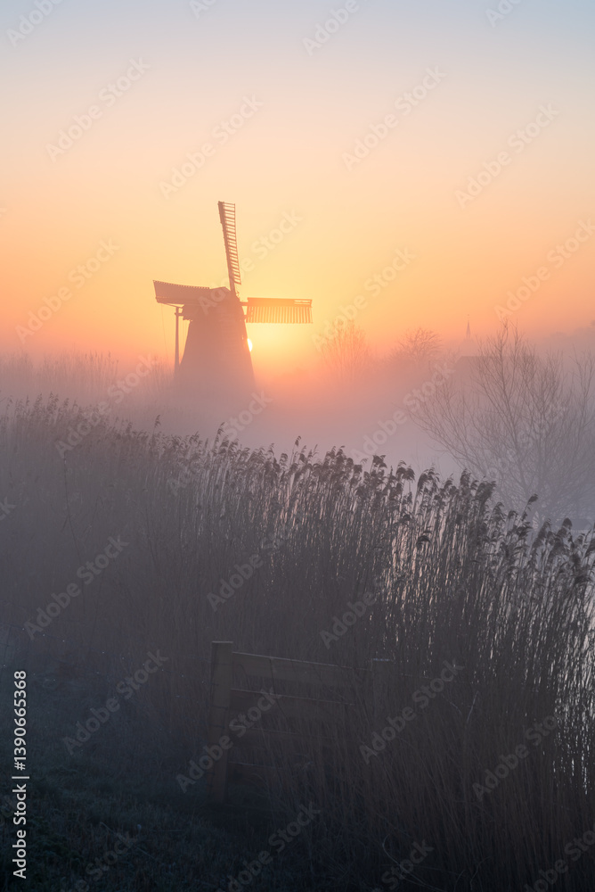 Dawn at a traditional, Dutch windmill in the spring fog.