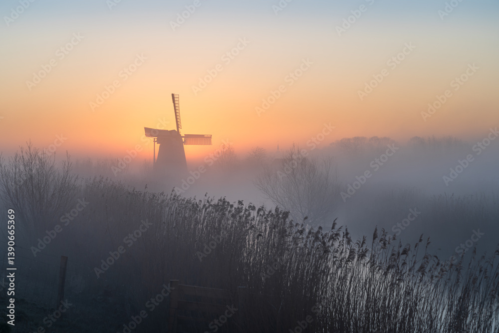 Dawn at a traditional, Dutch windmill in the spring fog.