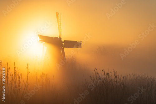 Quadro su tela Sunrise at a Dutch, traditional windmill and a canal in the spring fog