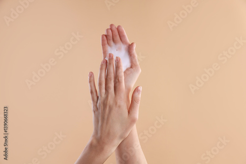 Woman washing hands with foaming soap on beige background, closeup. Hygiene