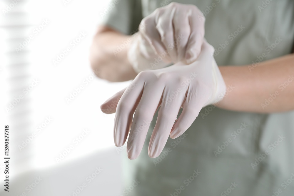 Fototapeta premium Medical worker putting on gloves in hospital, closeup