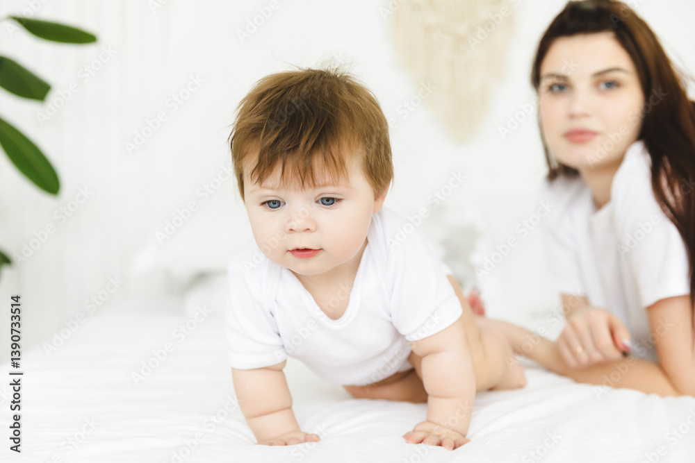 Portrait of beautiful mother playing with her 6-9 month old baby in bed