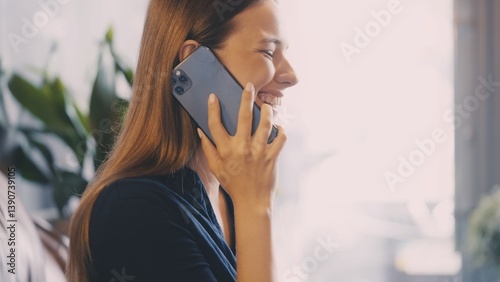 Attractive woman laughing sincerely while talking on smartphone, receiving good news