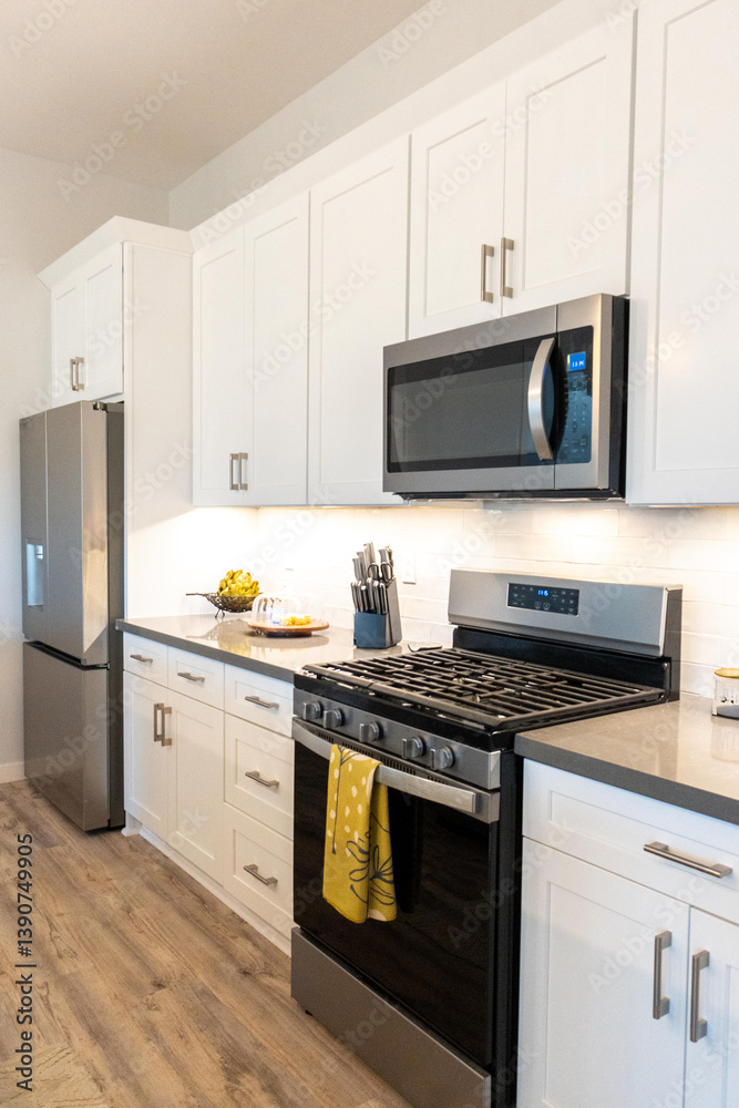 Fototapeta premium A kitchen with white cabinets, stove, refrigerator, and microwave