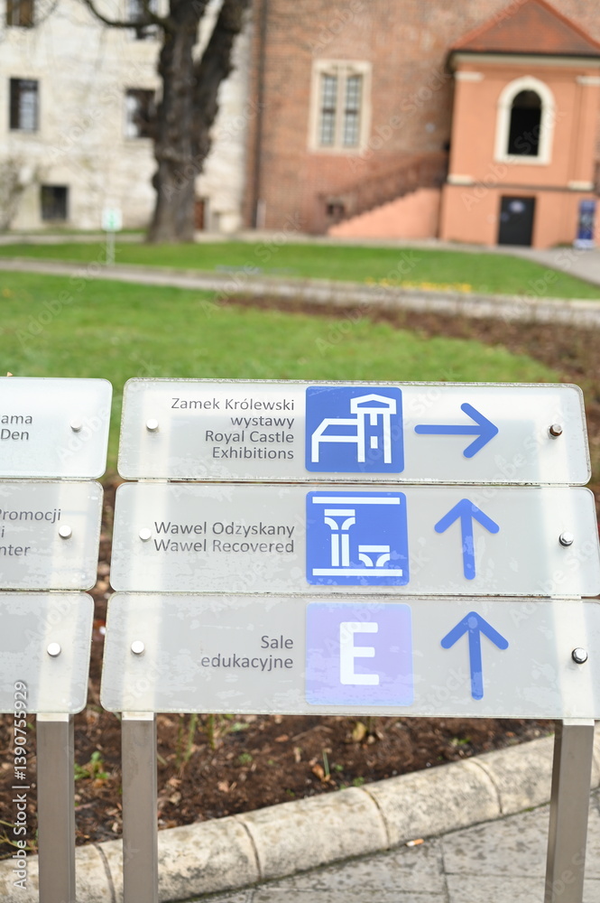 Fototapeta premium Tourist information signpost with direction arrows and icons. Travel navigation board showing museum, restroom, viewpoint, and information point. Concept of tourism, wayfinding, and urban infrastructu