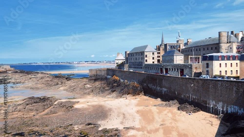 Skyline of the English Channel coast from fortress walls of the city of Saint-Malo during the ocean low tide against a blue sky. View of the old fortress National Fort. La Manche, Brittany, France