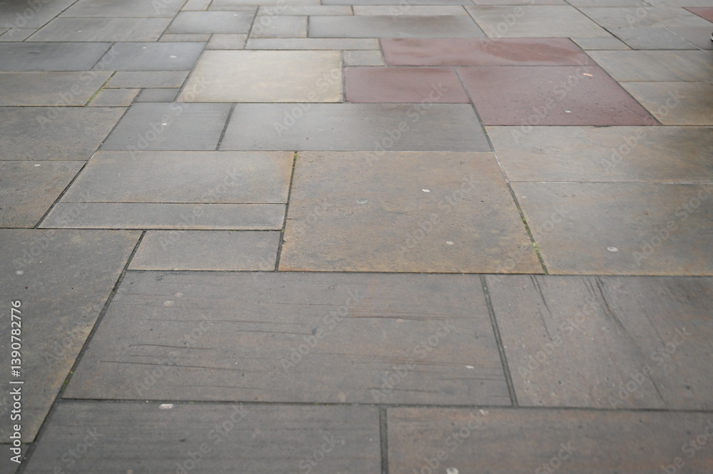 Fototapeta premium Modern stone pavement texture with square tiles in neutral gray and beige tones. Urban sidewalk background for architecture, design, and construction projects. Clean geometric pattern of paving slabs.