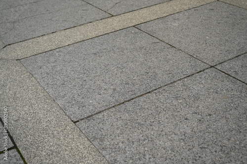 Stone pavement with geometric pattern of gray and beige tiles. Urban sidewalk texture with decorative lines