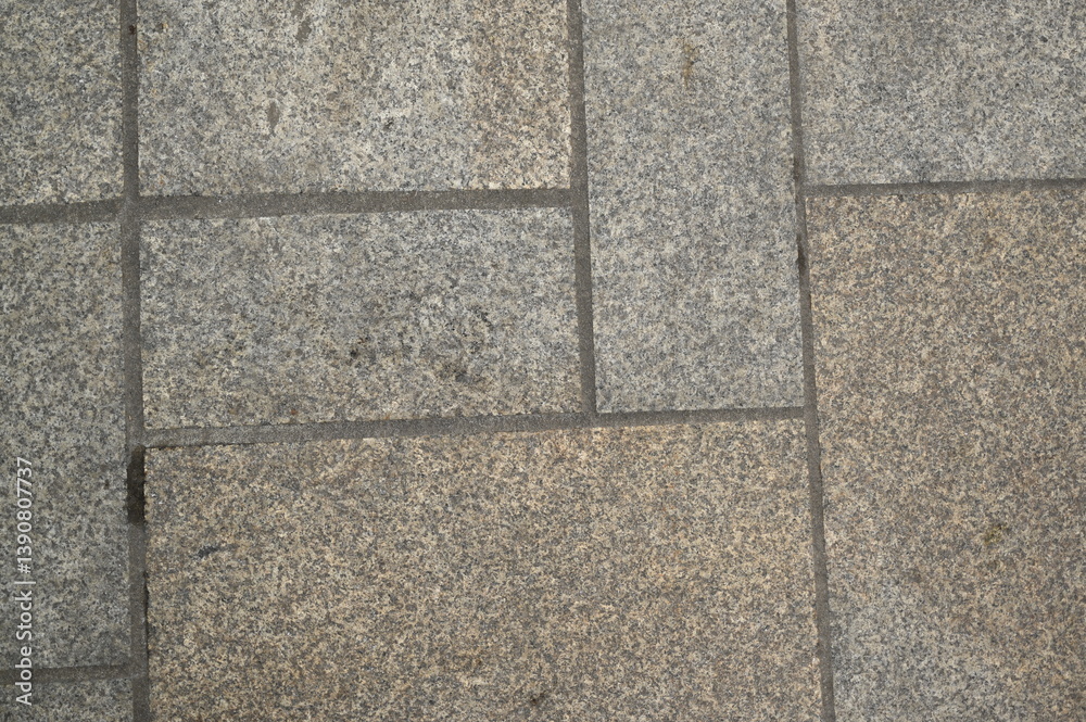 Fototapeta premium Granite pavement texture with geometric stone pattern. Urban background of grey and beige paving blocks — natural stone surface for architecture, design, and construction concepts.