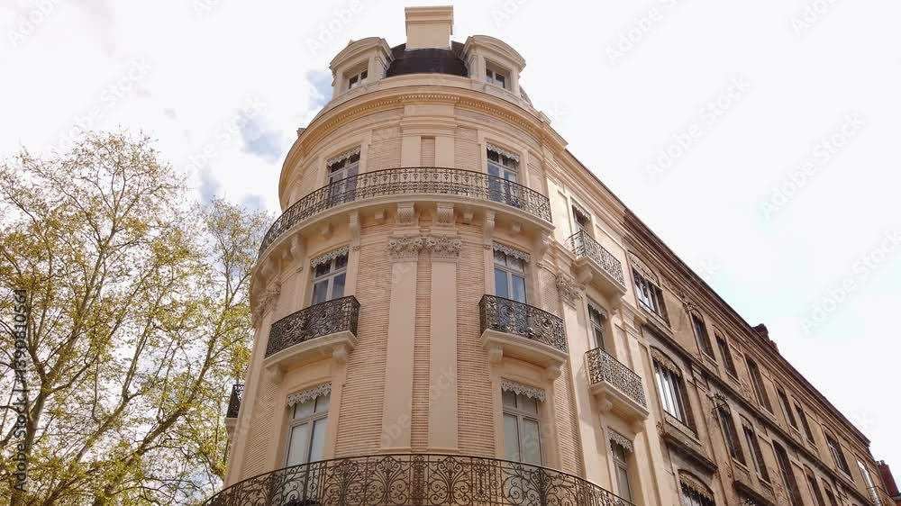 Façade arrondie rue François Verdier à Toulouse avec ciel bleu et arbre vert
