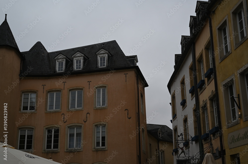 Obraz premium Narrow street with historic yellow buildings in Luxembourg City. Traditional European architecture with windows and tiled roofs — quiet atmosphere of the old town.