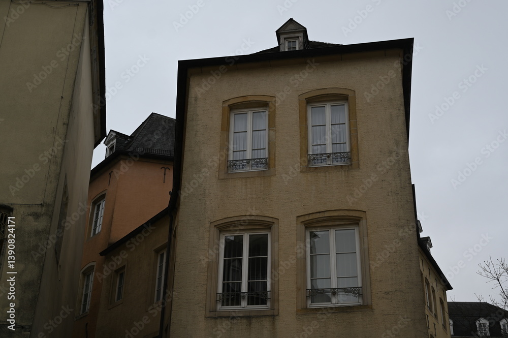 Obraz premium Narrow street with historic yellow buildings in Luxembourg City. Traditional European architecture with windows and tiled roofs — quiet atmosphere of the old town.