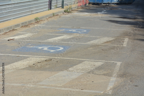 Parking area showing faded markings and debris near construction site on a sunny day