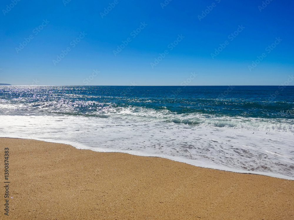 Serene beach scene featuring golden sand, sparkling blue ocean, and a clear sky. Ideal for travel, vacation, relaxation, and naturethemed projects. Represents peace escape. Serene beach scene featuring golden sand, sparkling blue ocean, and a clear sky. Ideal for travel, vacation, relaxation, and naturethemed projects. Represents peace escape.