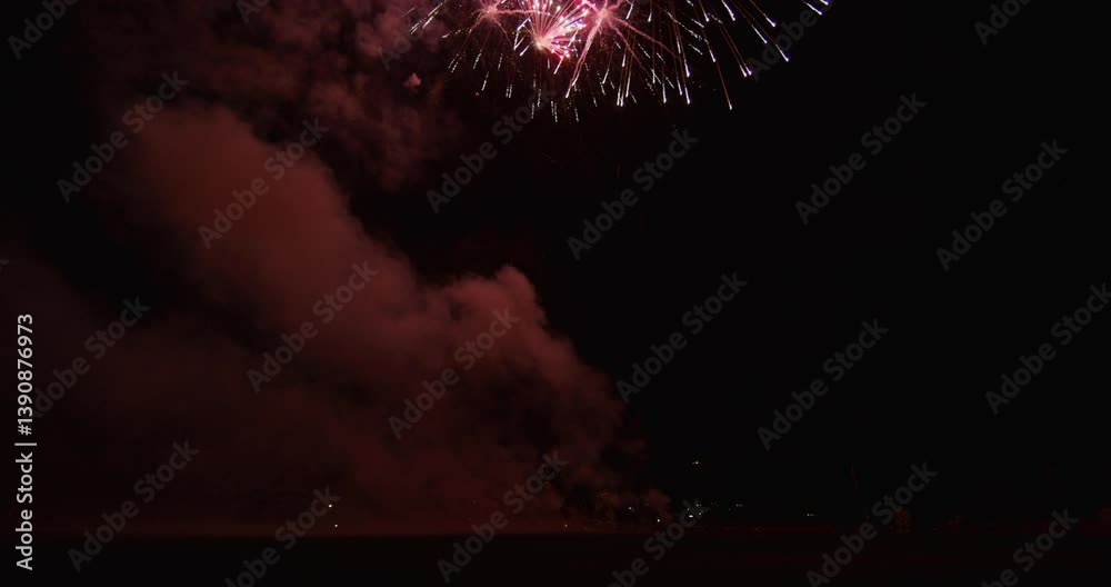 Beautiful aerial fireworks exploding in the night sky with smoke lingering