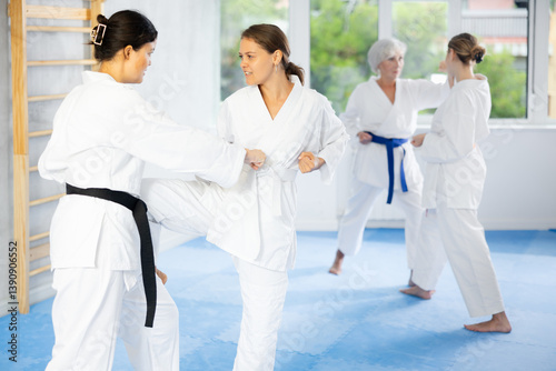 Wallpaper Mural Two young women in kimonos practicing karate techniques in group at gym Torontodigital.ca